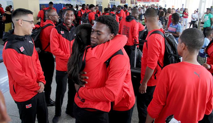 National hockey player Kristien Emmanuel, centre, brother of deceased Kwasi Emmanuel, is consoled by a female player at the Piarco International Airport yesterday.