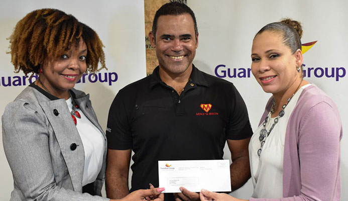 Michael Phillips (centre) of Phillips Promotions receives a cheque from Ayesha Boucaud-Claxton (right), Senior Manager, Group Corporate Communications and Kele Ransome, Corporate Communication Officer- CSR & Event of Guardian Group.