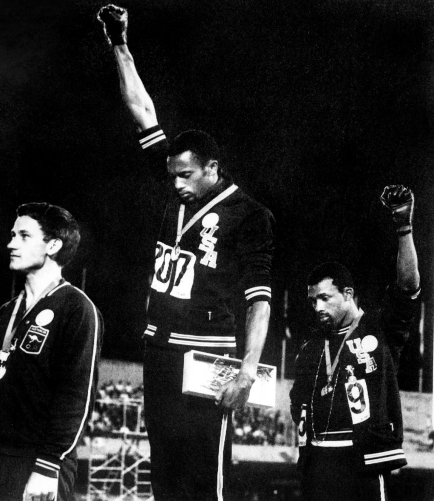 In this October 16, 1968 file photo, US athletes Tommie Smith (C) and John Carlos (R) raise their gloved fists in the Black Power salute to express their opposition to racism in the USA during the US national anthem, after receiving their medal for first and third place in the men’s 200m event at the Mexico Olympic Games. At left is Peter Norman of Australia who took second place. AFP PHOTO - -